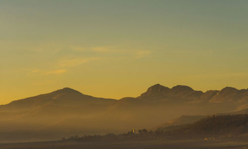 Scenic view of silhouette mountains against orange sky