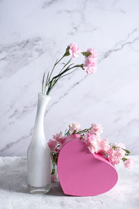 Pink carnations in a white vase and a gift in a pink box, gift valentine's day,