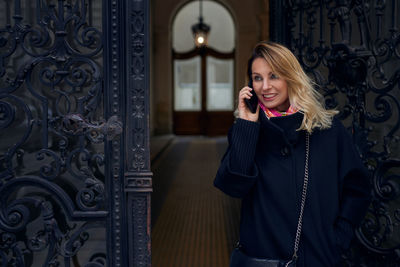 Woman talking on mobile phone while standing at doorway