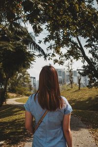 Rear view of woman standing against trees