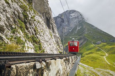 Overhead cable car over rocky mountains against sky