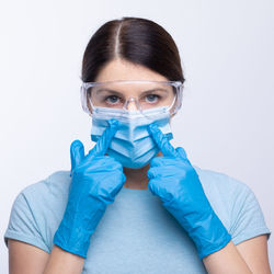 Portrait of doctor in mask wearing surgical glove against gray background