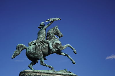 Low angle view of statue against blue sky