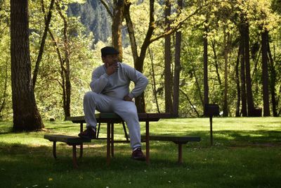 Thoughtful man sitting on picnic table in forest