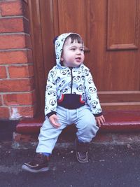 Portrait of cute boy standing against door