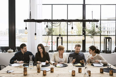 Business people discussing at decorated table against window in office