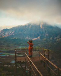 Rear view of woman standing against mountain