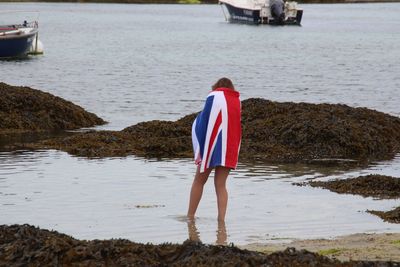 Rear view of woman wrapped in british flag at beach