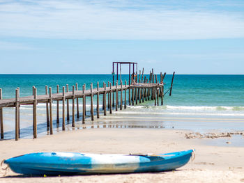 Deck chairs on beach by sea against sky