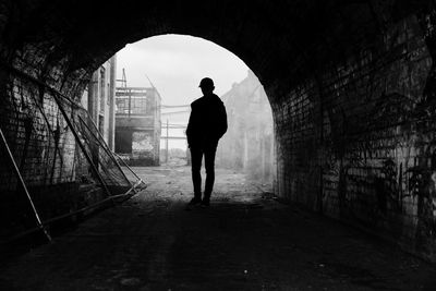 Rear view of silhouette man standing in tunnel