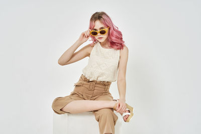 Portrait of young woman wearing sunglasses against white background