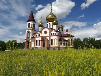 Church on grassy field against sky