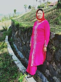 Portrait of smiling young woman standing against plants