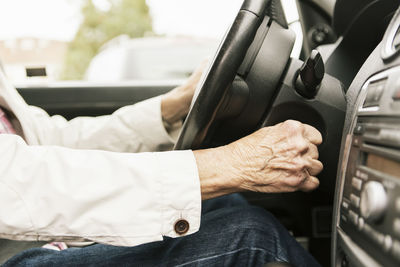 Senior woman starting car with key in ignition lock