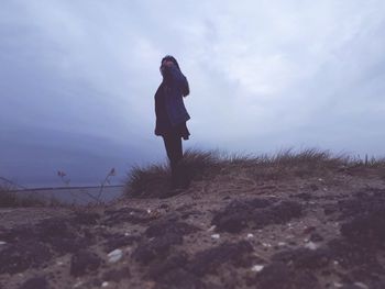 Side view of woman standing on field against sky