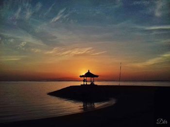 Silhouette lifeguard hut on beach against sky during sunset