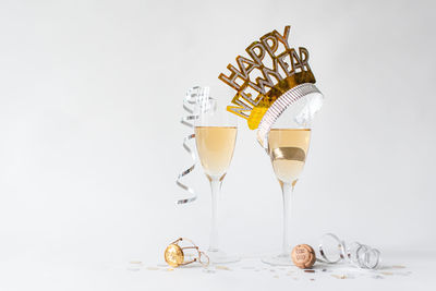 Glasses of champagne and happy new year hat on white background.
