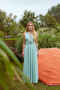 Portrait of young woman standing against plants