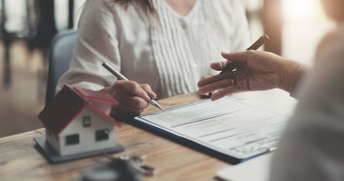 Midsection of woman holding paper while sitting on table