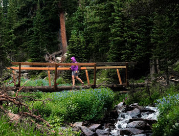 Man playing with bicycle on footbridge in forest