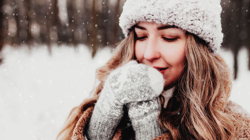 Beautiful young woman in snowy fancy winter woodland crossed hands because of cold weather