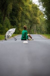 Rear view of man sitting on road