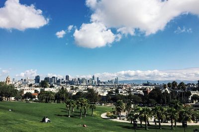 Park by cityscape against sky