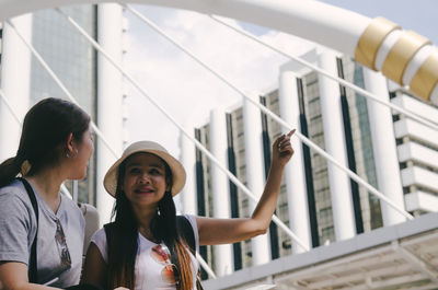 Smiling woman pointing while sitting by friend