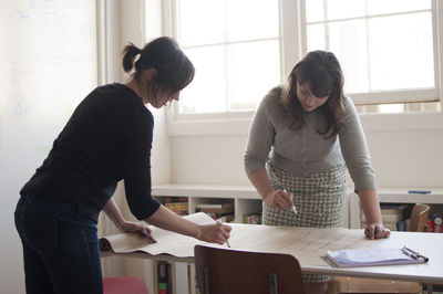 Businesswomen writing on paper at desk in new office