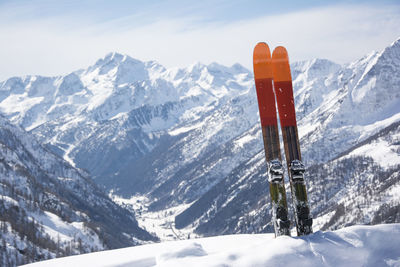 Close-up of skis against snow covered mountains 