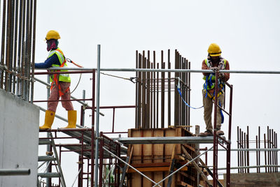 Workers at construction site against sky