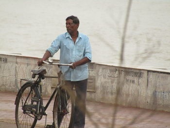 Man with bicycle standing at riverbank