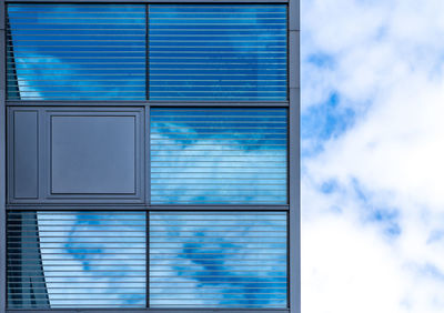 Low angle view of glass window against blue sky