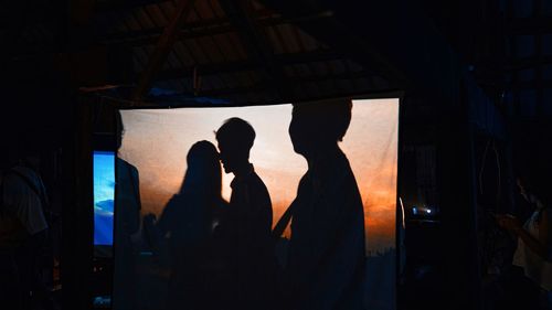 Silhouette people standing by window