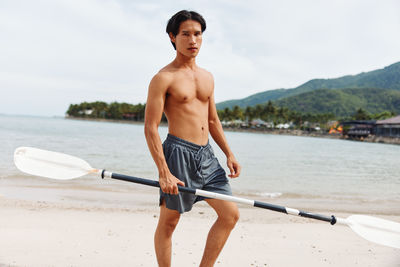 Rear view of shirtless man exercising in lake