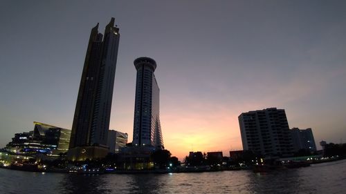 River in city against sky during sunset