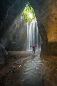 Rear view of man standing by waterfall