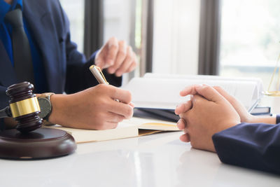 Midsection of man reading book on table