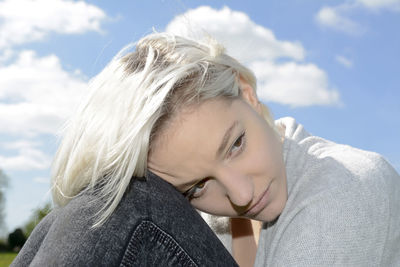 Sad woman looking away against sky