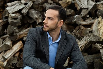 Portrait of young man sitting on log