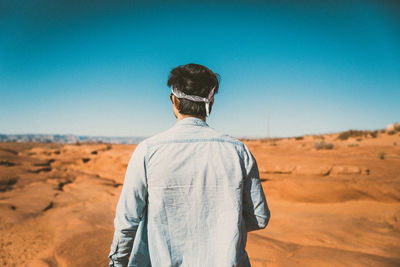 Rear view of man on desert against clear sky