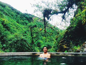 Portrait of woman in swimming pool against trees in forest