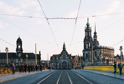 Railroad tracks leading towards buildings against sky