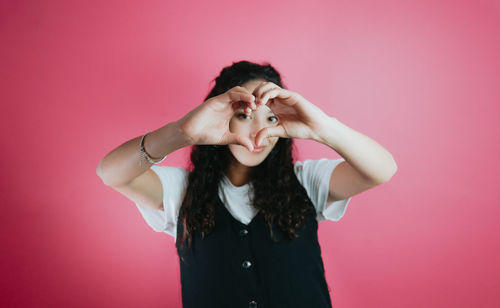 Young woman with arms raised against yellow background