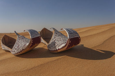 Close-up of sunglasses on sand at beach against sky