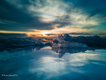 Frozen lake against sky during sunset