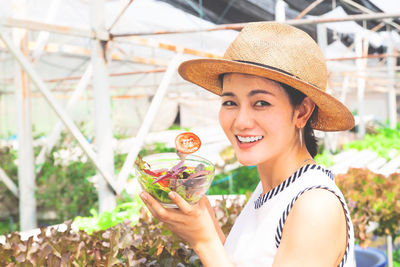 Portrait of smiling young woman holding hat