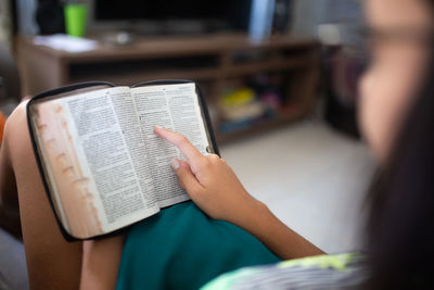 Midsection of woman reading book at home