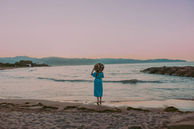 Woman standing on beach against clear sky