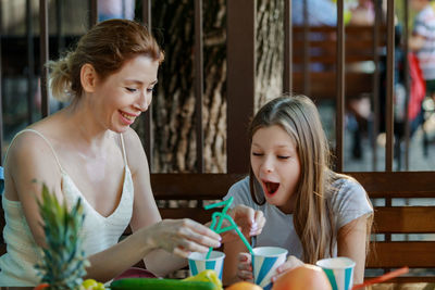 Smiling mother and daughter with fruits on table